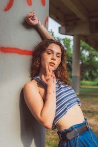 a woman leaning against a column with graffiti on it