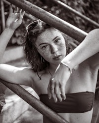 a woman in a bikini leaning against a railing