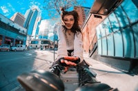 a girl sitting on top of a skateboard in a city